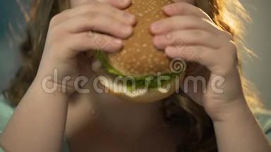 胖女孩<strong>双手拿</strong>着快餐汉堡，嚼着它，面部特写